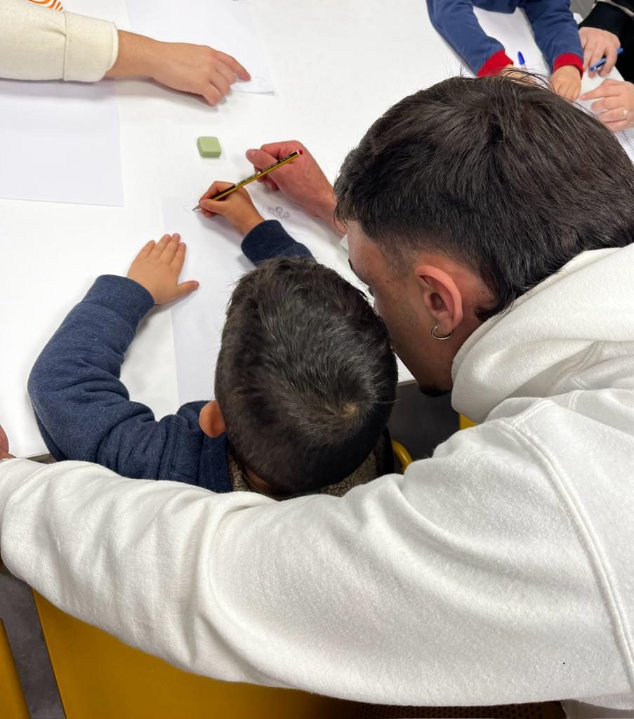 Un estudiante del Grado en Educación Infantil escribe junto a un niño durante la experiencia